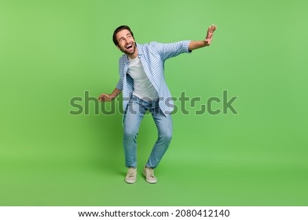 Full size photo of celebrate millennial guy dance wear shirt jeans footwear isolated on green color background