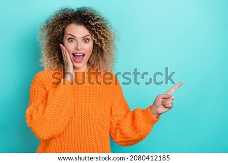 Photo of crazy lady direct finger empty space palm cheek wear orange knitted pullover isolated teal color background