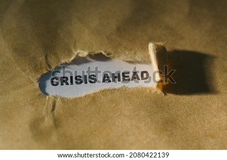 Economy and business concept. Torn paper in the middle of the sheet, inside on a white background the inscription - CRISIS AHEAD