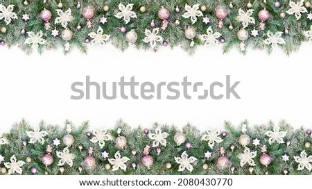 Christmas border with Christmas tree garland decorated with pink and gold glitter balls, white flowers. Background with pastel Christmas baubles close-up with copy space.