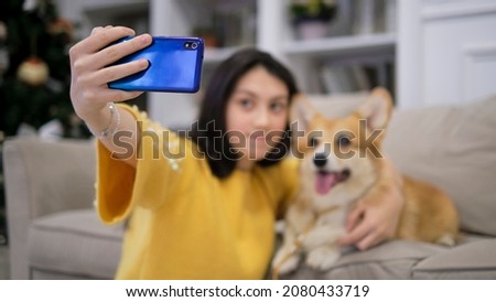Teenage girl taking selfie with her dog at home. Dog lover with domestic animal. Modern technology, people and animals concept.