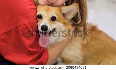 young teen girl hugging corgi dog with love eyes closed, smiling. Dog lover with domestic animal. soft selective focus