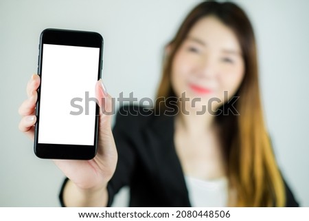 Portrait of stressed asian business woman showing empty white mobile screen. Caucasian female model isolated on white background. selective focus