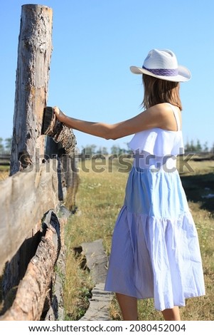 Beautiful hippie girl with horse on a ranch background, front view. The girl in the hat.