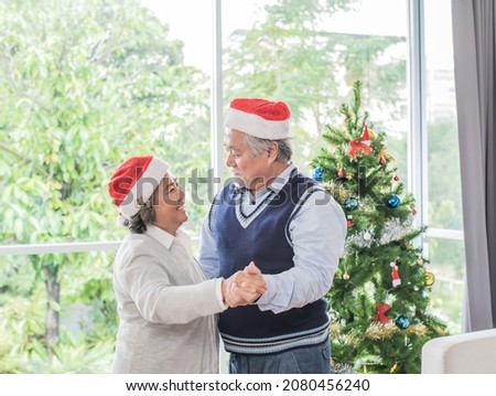 senior couple, husband and wife wearing christmas hats and dacing,backgroud tree.