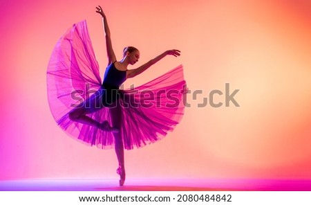 Beautiful young girl ballerina in pointe shoes and swimsuit silhouette on bright red background.