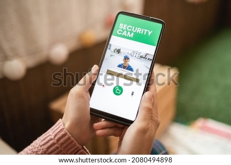 Delivery man ringing door bell on cctv secure camera system on mobile phone app Royalty-Free Stock Photo #2080494898