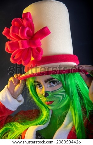 woman disguised as christmas, closeup portrait of mean, grumpy, unhappy, annoyed funny looking young woman, sitting in studio black background with santa claus costume green wig lady greem with smoke