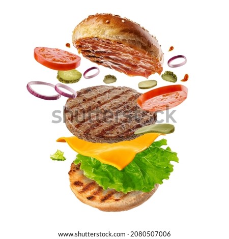 Flying burger. Big tasty hamburger with flying elements.  Explosive cheeseburger Royalty-Free Stock Photo #2080507006