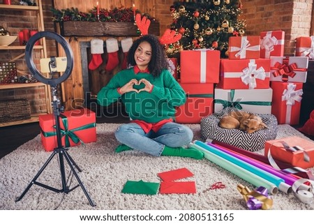 Full length photo of young black woman happy positive smile shoot video show fingers heart figure love newyear indoors