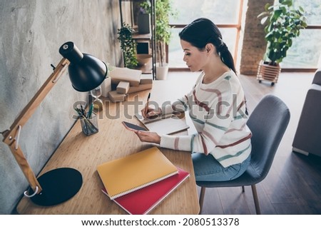 Photo of focused writer lady sit table write notes wear striped jumper in comfortable apartment home indoors