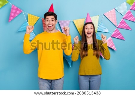 Photo of excited couple spouses have festive event raise fists up get gift present surprise isolated over blue color background