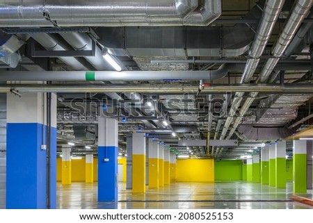 Underground parking of a commercial building with navigation system sensors. Air conditioning and ventilation ducts, fire extinguishing system pipes, electric cable channels under the ceiling.