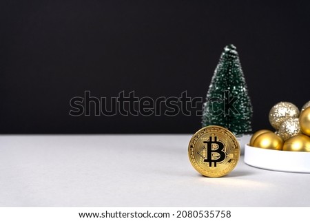 Gold coin with bitcoin sign with Christmas tree and Christmas balls on gray and black background. Cryptocurrency mining. Christmas gift