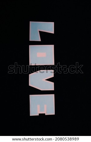 Letters of the word “LOVE” in blue on a white background. The letters are all isolated on a pure black background.