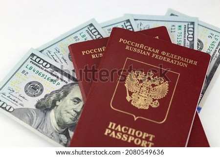 Russian international passports are on American dollars, 100 dollar bills. White background. Concept for tourism, border crossing, immigration. Selective focus. 