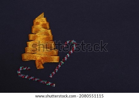 Christmas concept. Golden Christmas tree made of ribbons with a staff on a black background with copy space on top. Template for postcards, packaging, advertising. Banner.