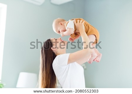 Portrait of attractive careful cheerful gentle affectionate girl playing with baby having fun nursing at light home flat indoors Royalty-Free Stock Photo #2080552303