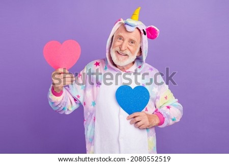 Photo of pretty handsome retired man nightwear overall smiling holding pink blue hearts isolated purple color background