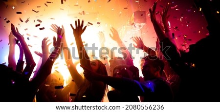 Photo of carefree clubbers blurred movement enjoy electro star performance raise hands up festival confetti modern neon filter