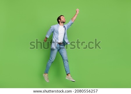 Full length profile side photo of young guy try to catch parasol look empty space jump isolated over green color background Royalty-Free Stock Photo #2080556257