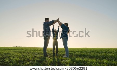 Family game outdoors. Child mom and dad play together building a house symbol at sunset. Happy family dreams of their own house in the summer park in the sun. Family happiness concept, childhood dream