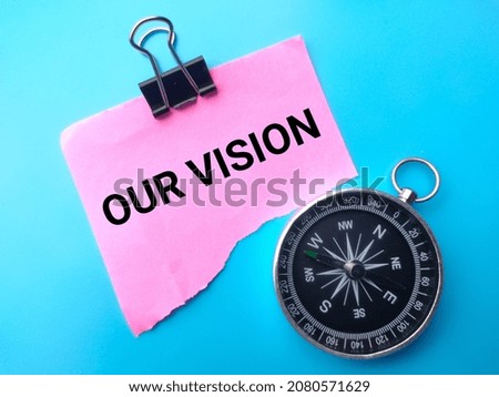 Compass and colored paper with text OUR VISION on blue background.
