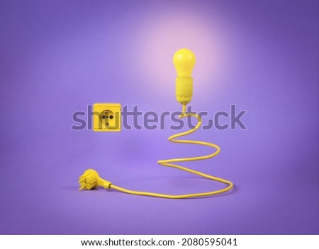 The concept of the New Year. Minimalism. Creative Christmas tree in the form of a light bulb with a cord on a purple background. Contemporary art. Place for text.