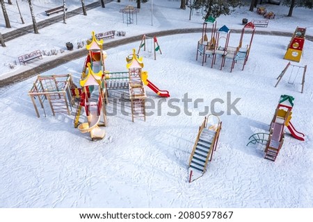 frozen colorful playground under snow in winter park at sunny winter morning. aerial view with drone.