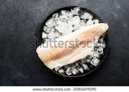 Fillet of cod fish. Saltwater white fish, raw before cooking. Healthy food ingredients. On a dark background.