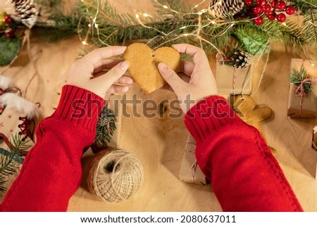 female hands hold a gingerbread in the form of a heart, which is an element of the decor of the Christmas advent calendar