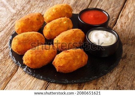 Basque golden Cod Croquettes Croquetas De Bacalao with sauces close up in the slate plate on the table. Horizontal
