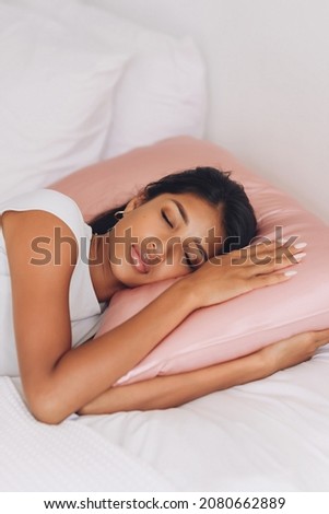 Beautiful Indonesian girl lying on a pink pillow with a silk pillowcase.
 Royalty-Free Stock Photo #2080662889