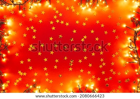 Red background with golden confetti in the form of stars. Valentines, Christmas or New Year day backdrop with lights. Flat lay style with minimalistic design.