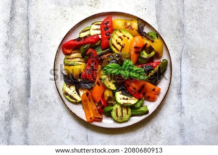 Grilled colorful vegetable : bell pepper, zucchini, eggplant on a plate over light grey slate, stone or concrete background. Top view with copy space. Royalty-Free Stock Photo #2080680913