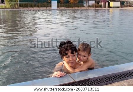 Grandmother and grandson swim together in the pool. Outdoor, autumn, thermal.