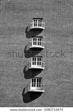 Wall of houses with four windows in a row one below the other, large shadows, symmetry