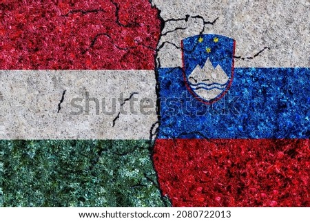 Hungary and Slovenia painted flags on a wall with grunge texture. Hungary and Slovenia conflict. Slovenia and Hungary flags together. Hungary vs Slovenia