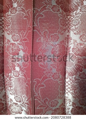 Red batik curtains with floral motifs.