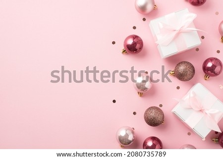 Top view photo of pink christmas decorations balls confetti and white gift boxes with pink ribbon bows on isolated pastel pink background with copyspace