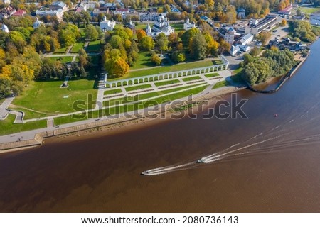 Panoramic aerial view of the Great Bridge and the Volkhov River in Veliky Novgorod, autumn trees on a sunny day. Motor boat and speed boat