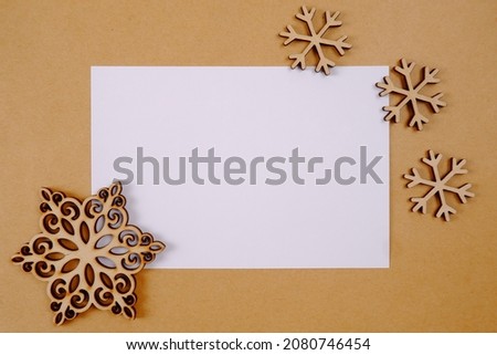 Wooden Christmas snowflakes on the background of a blank sheet of craft paper with a place for text. Natural eco-friendly Christmas decorations, blanks for creativity, preparation for the New Year.