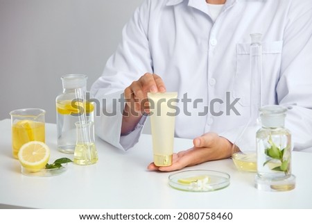 Lemon extract with sliced lemon transparent podium in laboratory , petri dish in a white background , green leaf  in a test tube and doctor for cosmetic jar advertising , photography science concept