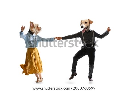Social dancing. Dynamic portrait of stylish dancers, young man and woman in vintage attire headed of dog's heads dancing swing isolated on white background. Contemporary art collage.