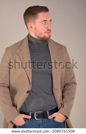 portrait of a thoughtful young man of European appearance in a coat and glasses