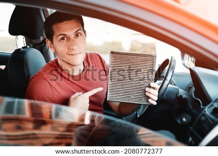 Man changes old polluted filter for the ventilation of the car interior. Dangerous particles of pollen, bacteria and viruses are collected in the air condition system Royalty-Free Stock Photo #2080772377