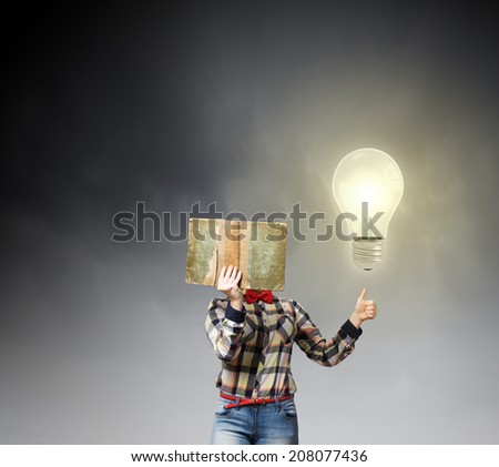 Woman in casual wear hiding her face behind book
