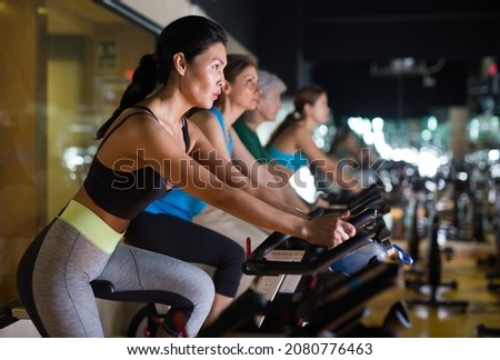 Asian woman in sportive activewear training on bike in spin class at gym Royalty-Free Stock Photo #2080776463
