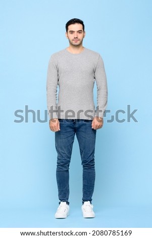 Full length portrait of standing young handsome Caucasian man looking at camera in isolated studio blue background Royalty-Free Stock Photo #2080785169