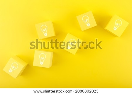 Concept of idea, creativity, start up or brainstorming. Light bulbs drawn on yellow toy cubes on yellow background 